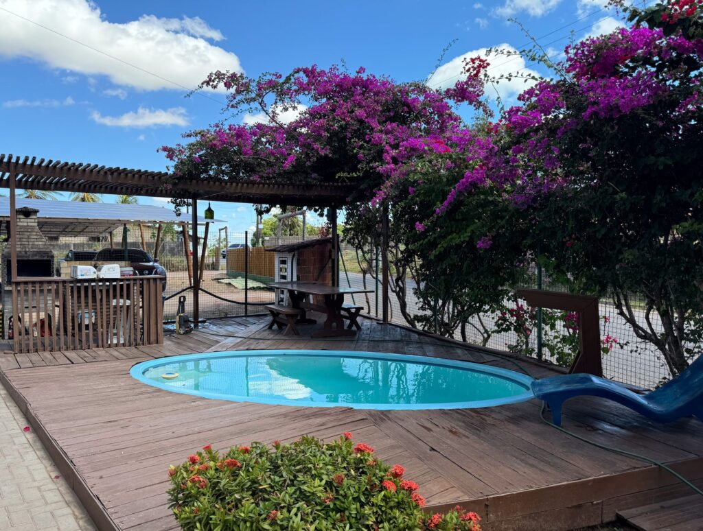 Piscina com deck de madeira e flores no Pecém Hotel